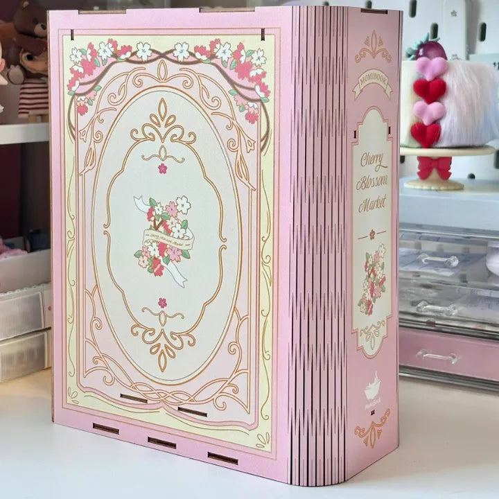 Book Nook - Sakura Bazaar, un kit créatif pour construire un diorama miniature. Parfait pour décorer une bibliothèque ou comme cadeau original pour un amoureux des livres. Par Nookette.