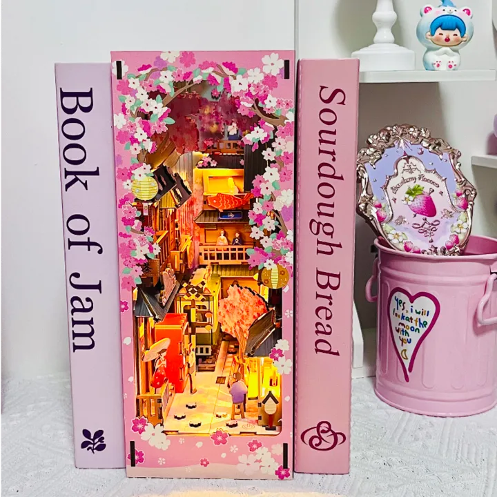 Book Nook - Sakura Bazaar, un kit créatif pour construire un diorama miniature. Parfait pour décorer une bibliothèque ou comme cadeau original pour un amoureux des livres. Par Nookette.