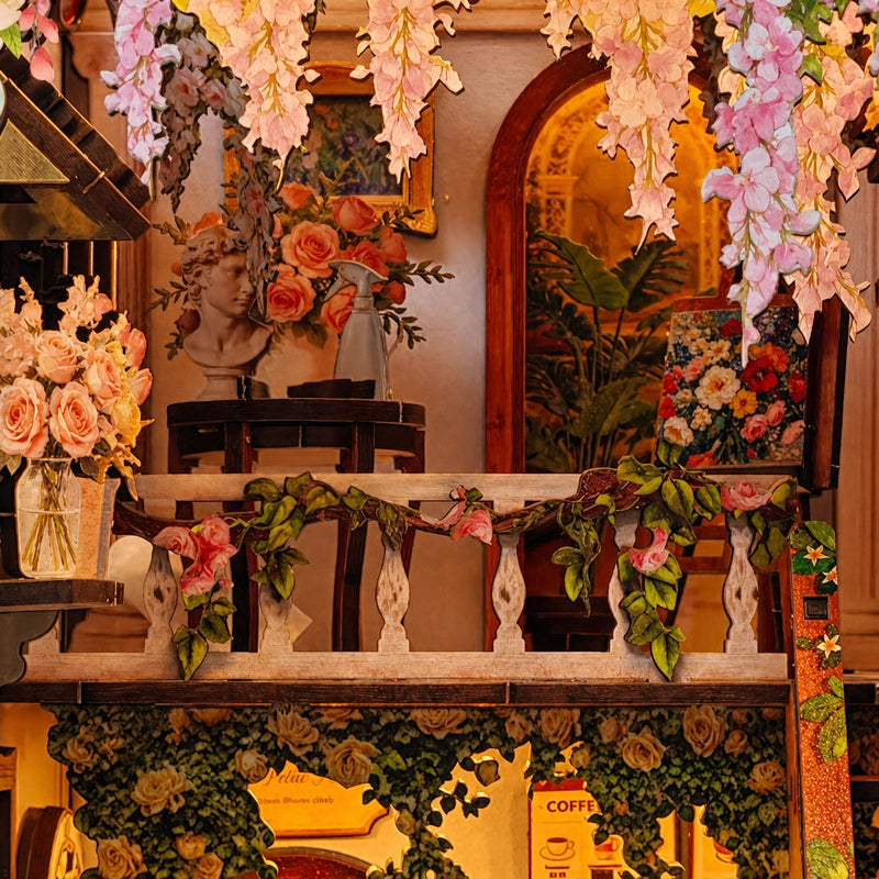 La galerie supérieure réunit bouquets, plantes et petit coin d’artiste. La balustrade fleurie et les suspensions végétales relient les deux niveaux du décor.